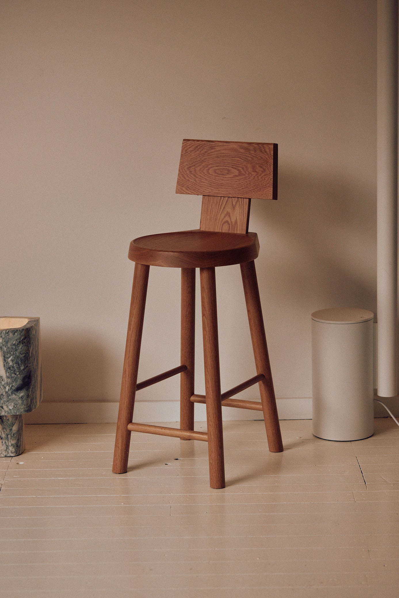 Timber bar stool with round seat and low backrest in minimalist interior