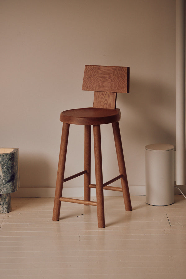 Timber bar stool with round seat and low backrest in minimalist interior